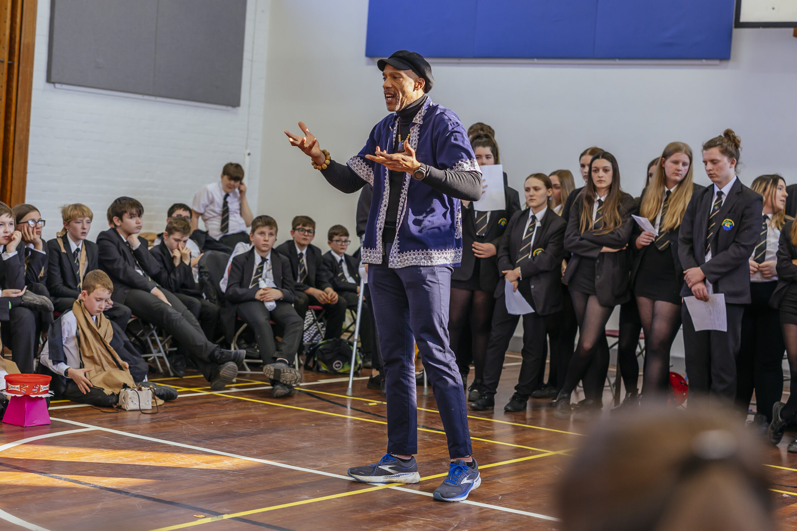 facilitator in blue jacket leading workshop in school sports hall