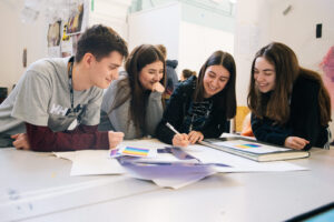 Group of four students working around a table and smiling